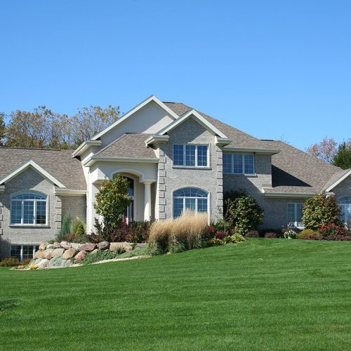 luxurious brick executive house with blue sky and green grass